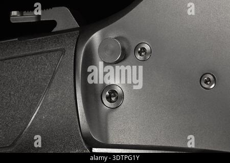 Large safesy button and hammer behind on a modern black lever action rifle in a close-up with a black background. Stock Photo