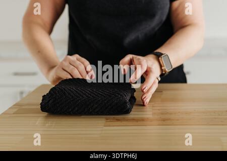 Close up of faceless female folding hand towel at kitchen counter Stock Photo