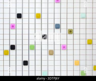 Wall strewn with multicolored electrical switches and outlets, and squares of various colors and sizes arranged in grid, creates creative and colorful Stock Photo