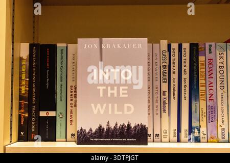 Close-up of the non-fiction book "Into the Wild" by Jon Krakauer displayed on a bookshelf. Stock Photo