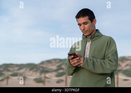 Young man using smartphone on sandy dunes Stock Photo