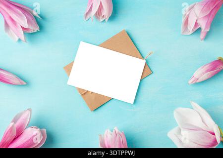 Blank greeting card and envelope in pink magnolia flowers frame on turquoise background. Floral mockup with copy space. Wedding invitation. Mothers Stock Photo