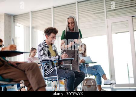 Group of college students attending lecture in university hall. Group of college students attending lecture in university hall. Diverse university stu Stock Photo