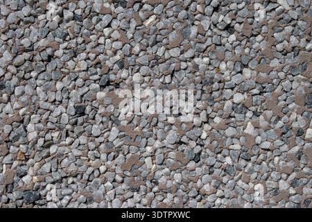 Full frame close-up of a pebble dash wall texture with small grey stones embedded in mortar. Stock Photo
