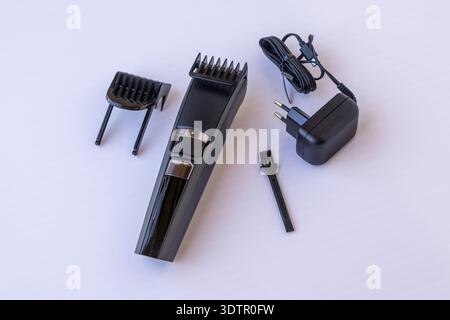 Rechargeable cordless electric hair trimmer and beard grooming kit. Complete professional set with adjustable combs and power adapter, isolated on whi Stock Photo