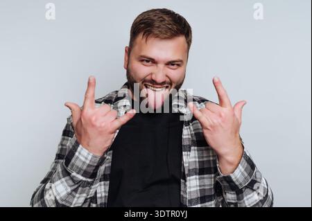 A young man stands confidently in a simple studio with a bright background. Stock Photo