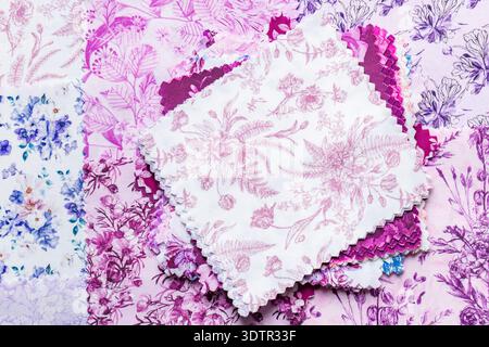 Fabric patchwork squares, in various colours and designs, stacked background backdrop. Sewing craft needlework concept. Stock Photo