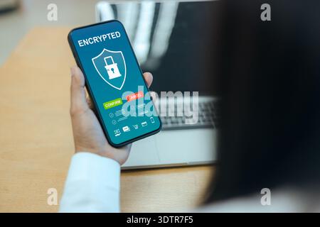 Close up of a person holding a smartphone with an encrypted security interface, featuring shield and lock icons for mobile data protection and digital Stock Photo