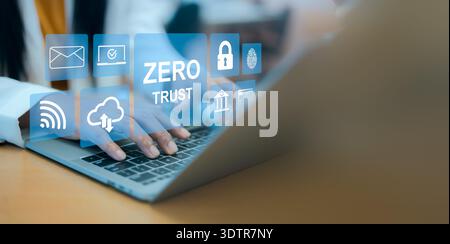 Business woman working on laptop with virtual zero trust interface, featuring identity verification, lock, fingerprint, and cloud icons for advanced c Stock Photo
