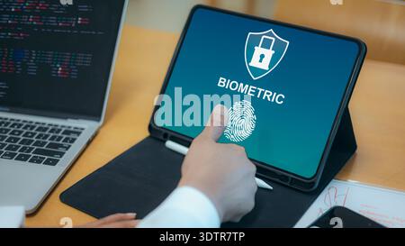 Close up of a person using a fingerprint scanner for biometric authentication on a digital tablet, featuring security shield and lock icons with a lap Stock Photo