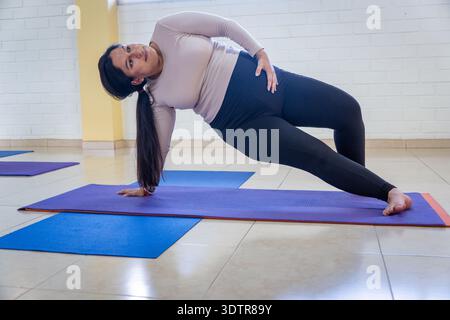 Woman performing a modified side plank on a yoga mat Stock Photo