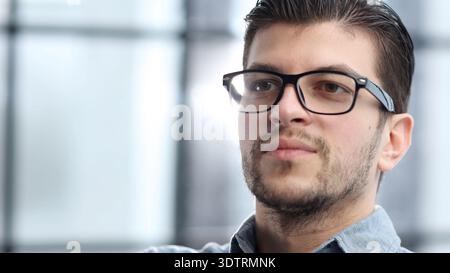 A man's face in close-up with glasses looks thoughtfully away Stock Photo