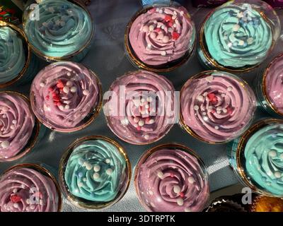 colorful cupcakes with swirled frosting in containers concept of bakery, party, sweets Stock Photo