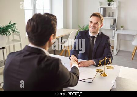 Professional lawyer makes hand shake gesture with client Stock Photo