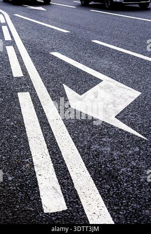Traffic sign white arrows on asphalt road close up. Arrow sign on asphalt Stock Photo