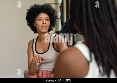 Large studio microphone is hanging between chairs near window blinds in small beige room Stock Photo
