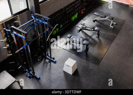 White plyometric box is sitting on black rubber floor near blue cable machine and benches Stock Photo