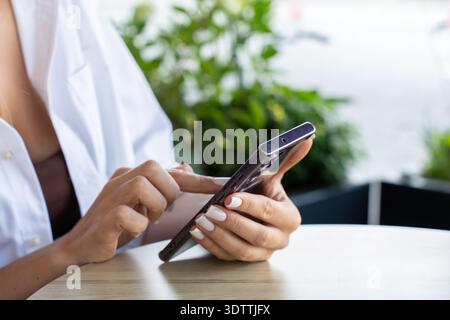 Stylish young adult engaged in texting and social media, enjoying a moment of connection in a modern city setting. Stock Photo