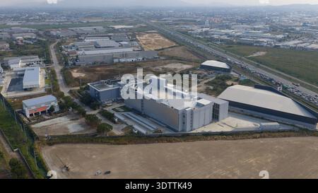 Aerial view of the sprawling industrial landscape, revealing a modern data center amidst the infrastructure, casting shadows on the muted earth, Chang Stock Photo