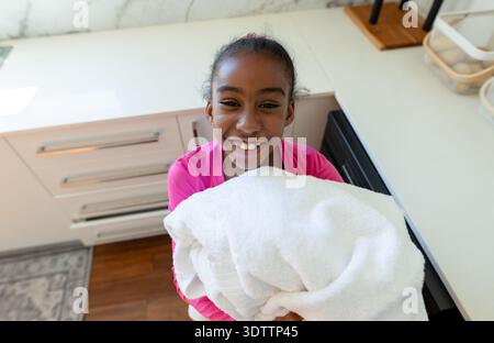 Large stack of white towels is sitting on white quartz countertop in modern home kitchen Stock Photo
