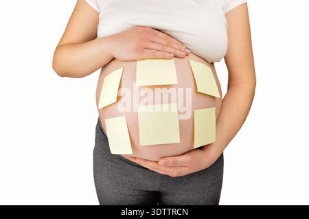 Shot of an unidentifiable pregnant woman with adhesive notes stuck to her belly Stock Photo