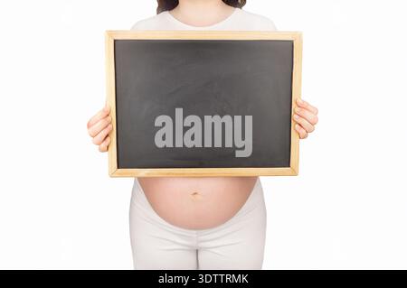 A cropped image of a pregnant woman holding up a blackboard with a copy space Stock Photo