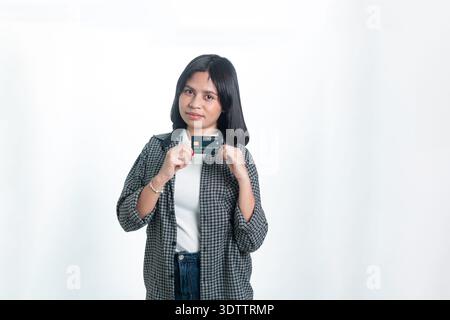 Portrait of a young Indonesian woman in a flannel shirt holding a credit card or student ID card. Concept of tuition fees, scholarship funds, and digi Stock Photo