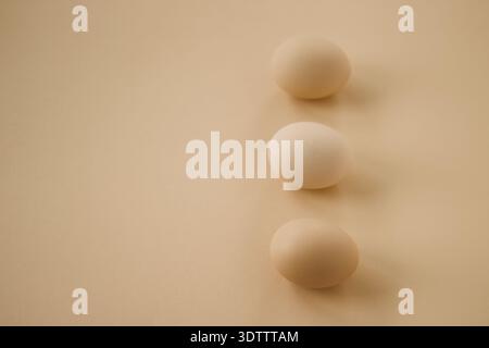 Three brown eggs on minimalist beige background Stock Photo