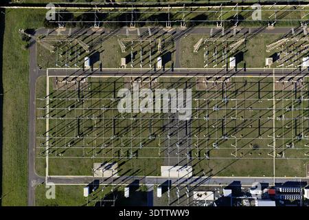 Aerial view of a power distribution substation, its metallic framework casting geometric shadows on the green surroundings, Civitavecchia, Lazio, Ital Stock Photo