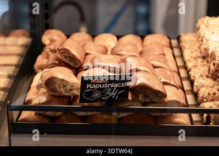 Polish cabbage pastries (kapuśniaczki) in a bakery display tray with price sign, savory baked goods on sale in a pastry shop. Stock Photo