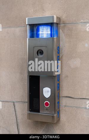 Contemporary security intercom unit installed on a stone exterior wall. Brushed stainless steel emergency communication panel featuring a built-in Stock Photo