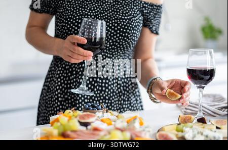 Girl Drinks A Glass Of Wine In The Kitchen With An Appetizer Cheese Plate On A Romantic Dinner Stock Photo