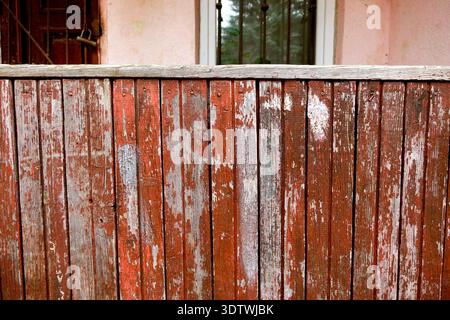 The wooden fence shows signs of wear with old paint peeling off. A building can be seen in the background, creating a simple outdoor scene during the Stock Photo