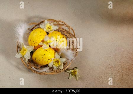 Top view of Easter basket with golden eggs, feathers and daffodils Stock Photo