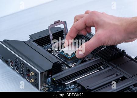 Hand installing desktop processor into motherboard socket, computer assembly process and high performance pc building concept Stock Photo