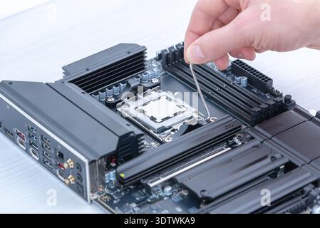 Securing cpu in motherboard socket with retention bracket, detailed computer hardware installation and pc assembly process Stock Photo