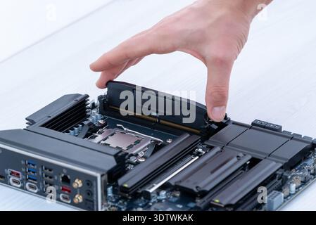 Hand inserting ddr5 memory module into motherboard slot, computer upgrade and high speed ram installation concept Stock Photo