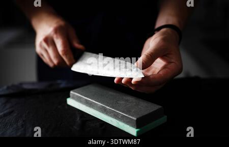 Man Hands Sharpening Kitchen Knife With Whetstone, Slow Motion Video, Close Up View Stock Photo