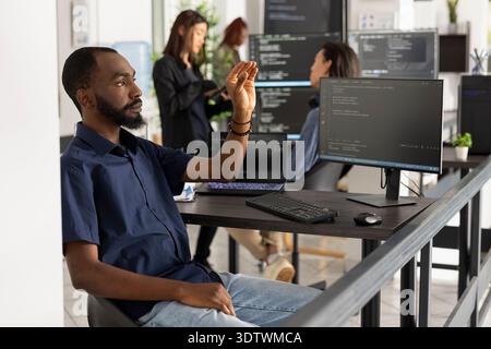 Male software programmer engages with invisible holographic interface in startup office, exploring augmented reality and futuristic human computer interaction for innovative tech solutions. Stock Photo