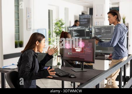 Asian female technology professional reacts to bad news on device screen, signaling computer crash, virus infection, or network error during office work in a high pressure IT environment. Stock Photo