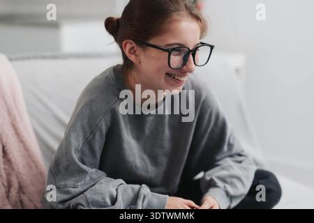 Happy, Laughing Girl In Glasses On The Sofa In A Light Room Stock Photo
