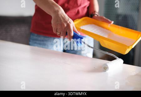 Girl Uses A Roller To Paint A Wooden Board White In A Close-Up View Stock Photo