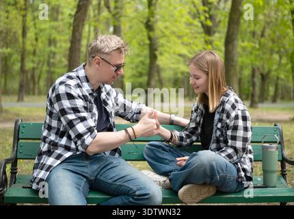 Happy Father And Little Daughter Sitting On A Bench Playing A Thumb War Game In Family Look Stock Photo