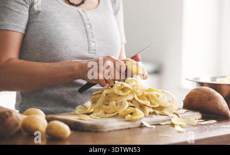 Woman Peeling Raw Potatoes With A Knife For Dinner Stock Photo