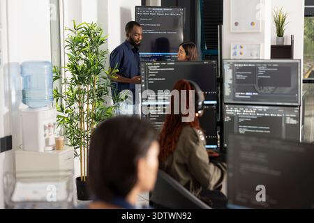 Professional team of developers conducting software code review in open workspace. Group collaboration focused on programming, data analysis and technical strategy in modern office. Stock Photo