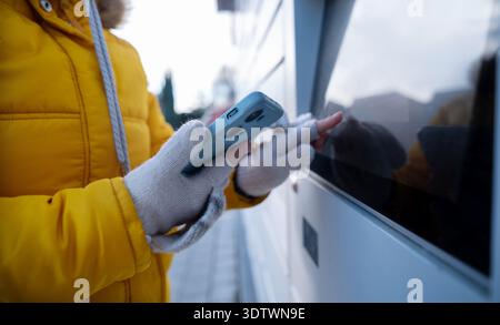Girl Picking Up A Parcel From A Parcel Automated Locker Enters The Receiving Code In Winter Stock Photo