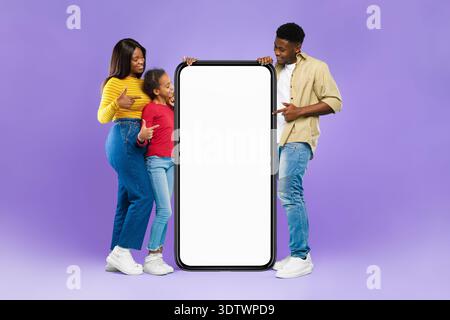 Family Members Stand Together Holding a Large Blank Tablet With a Purple Background Stock Photo