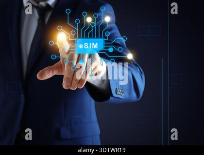 Businessman activating eSIM microchip on virtual screen, closeup. Dark background Stock Photo