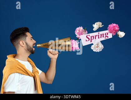 Hello Spring. Man using loudspeaker on blue background. Flowers flying out of device Stock Photo