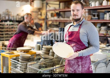Enthusiastic ceramicist demonstrating handcrafted plates in ceramic studio Stock Photo